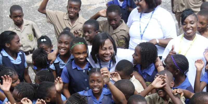 Pearl Jarrett laughing with Jamaican schoolchildren and volunteers
