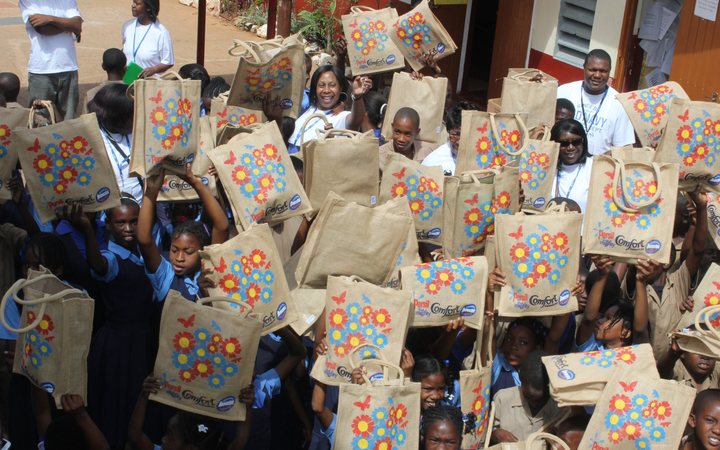 Pearl Jarrett with Jamaican schoolchildren holding up their new bags